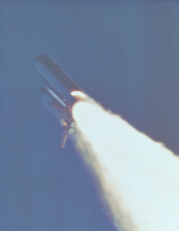 Imagen del sólido propulsor de cohete derramando combustible, segundos antes de la explosión. La pequeña flama visible al costado del cohete es el sitio de la falla del O-ring (junta tórica). By NASA (Great Images in NASA Description) [Public domain], via Wikimedia Commons